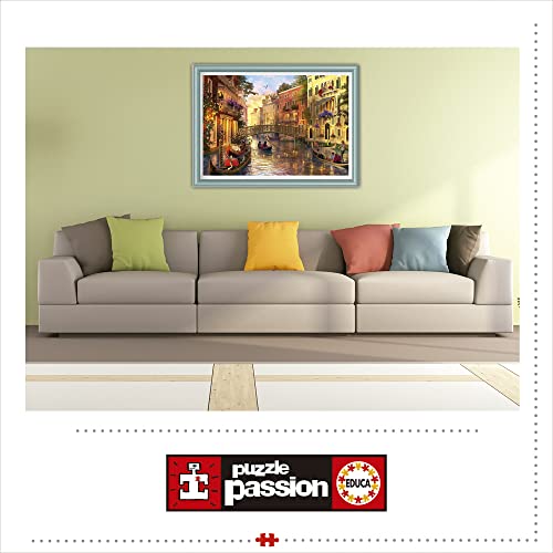 A framed puzzle of a Venetian canal scene hanging above a modern beige sofa.