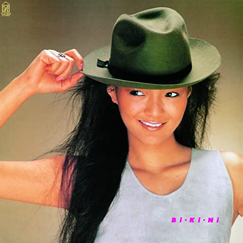 Woman with long dark hair and a fedora, album cover art.