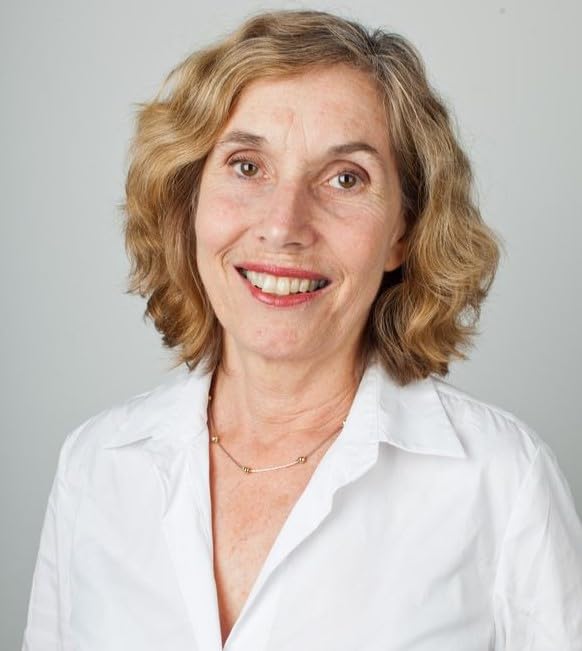 Headshot of a smiling woman with wavy brown hair and a white shirt.