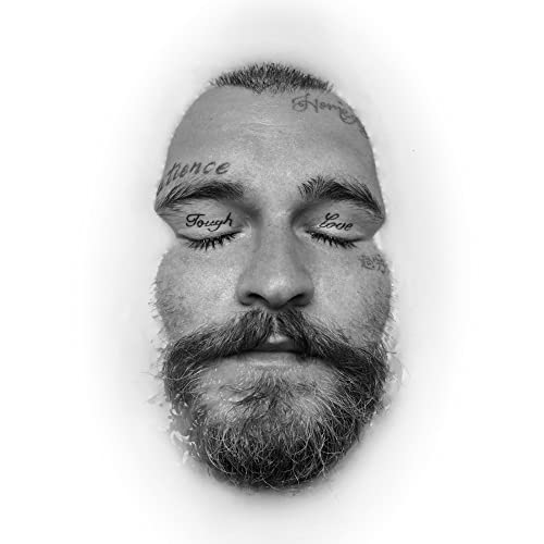 Black and white portrait of Teddy Swims with face tattoos, eyes closed.