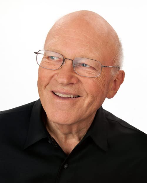 Headshot of a smiling older man with glasses and a shaved head.