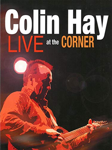 Colin Hay playing guitar on stage, bathed in red light, for Live at the Corner.