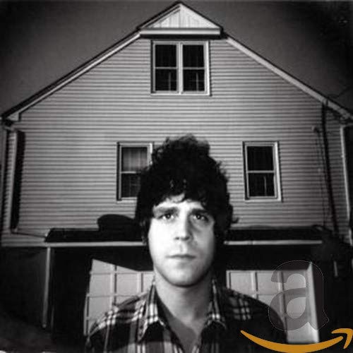 Black and white album cover featuring a man in front of a house.