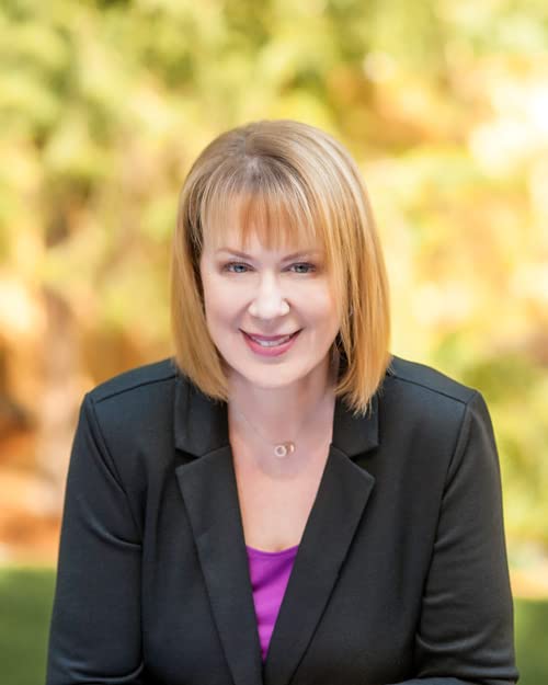 Woman with blonde hair smiling, wearing a black blazer.
