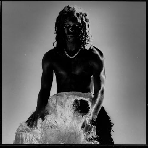 Black and white portrait of a shirtless person with long hair and jewelry.
