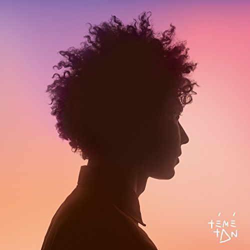 Silhouette of a person with curly hair against a colorful sunset.