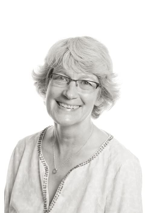 Black and white portrait of author Elly Griffiths, smiling and wearing glasses.