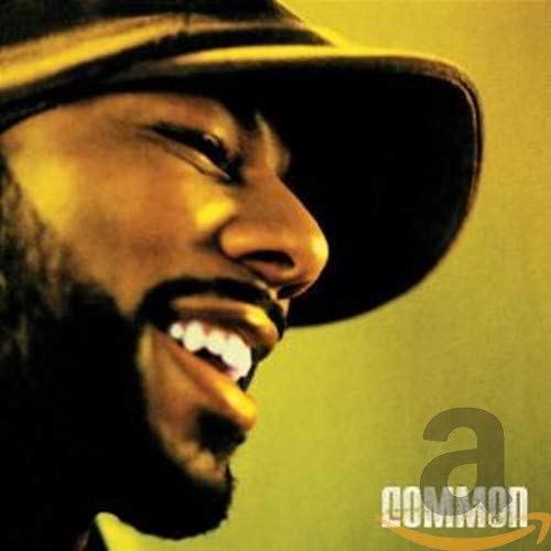 Close-up of Common smiling, wearing a hat, on a yellow background.
