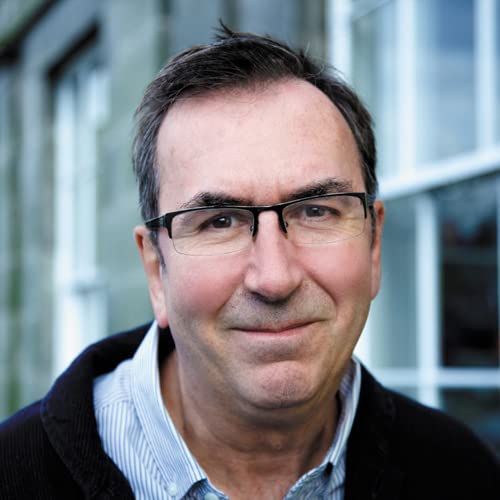 Middle-aged man with short brown hair and glasses wearing a striped shirt and jacket.