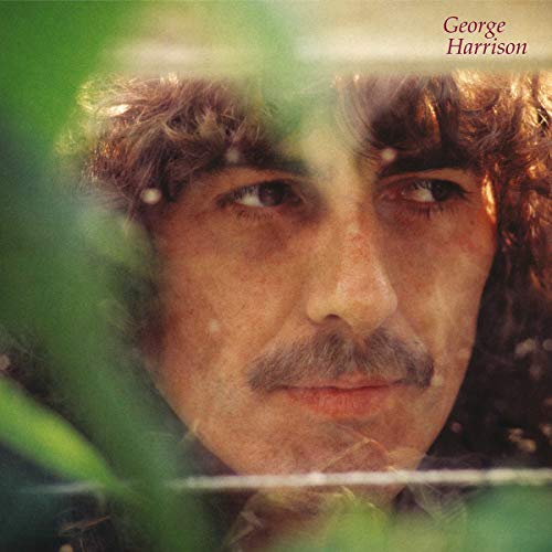 Close-up of George Harrison's face with greenery in the foreground and blurred background.