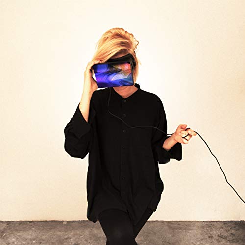 Woman in black shirt covering face with a glowing, colorful device.