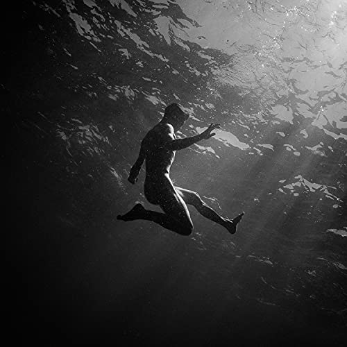 Silhouetted figure underwater, reaching towards light filtering through the surface.