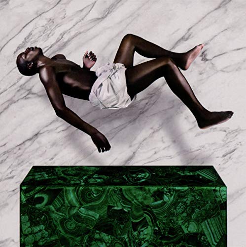Black man reclining on a green marble pedestal, white cloth draped.