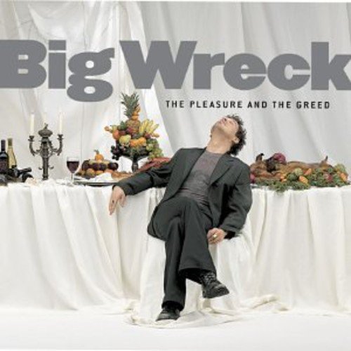A man in a suit sits at a banquet table filled with food and wine.