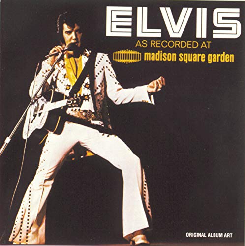 Elvis Presley in a white jumpsuit performing with a guitar onstage.