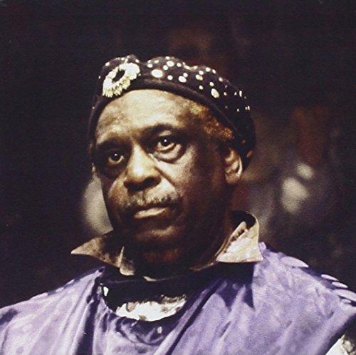 Close-up portrait of Sun Ra wearing a decorated hat and dark clothing.