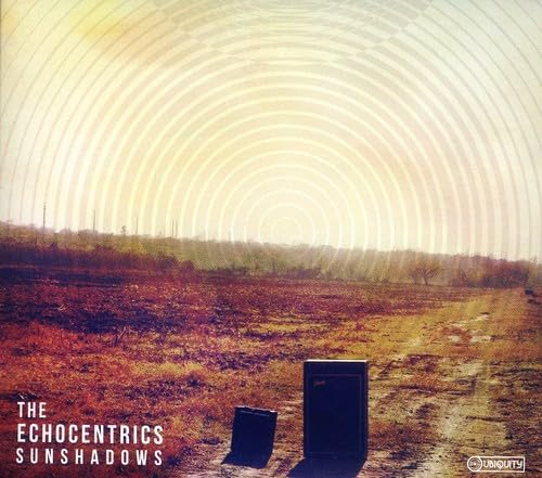 AlbumHazy field landscape with two black speakers under concentric white circular patterns.