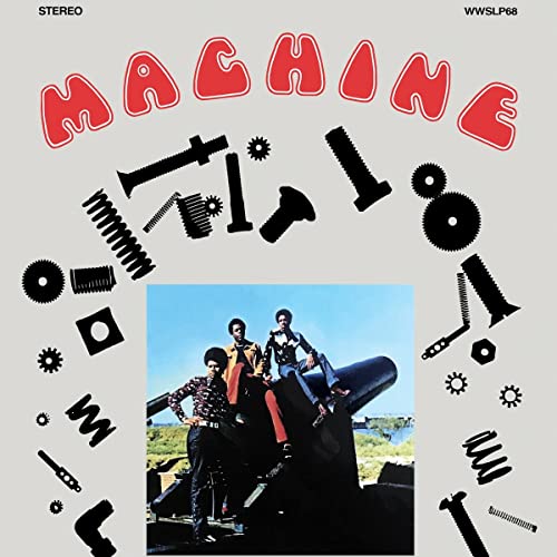 Album cover for "Machine" featuring a band posing with aircraft parts.