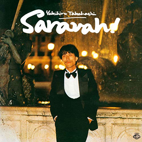 Yukihiro Takahashi in a tuxedo stands before a fountain and lights.