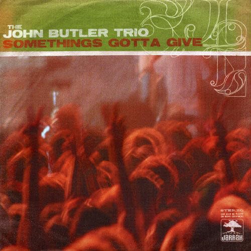 CD cover for John Butler Trio’s “Something’s Gotta Give” with abstract red imagery.