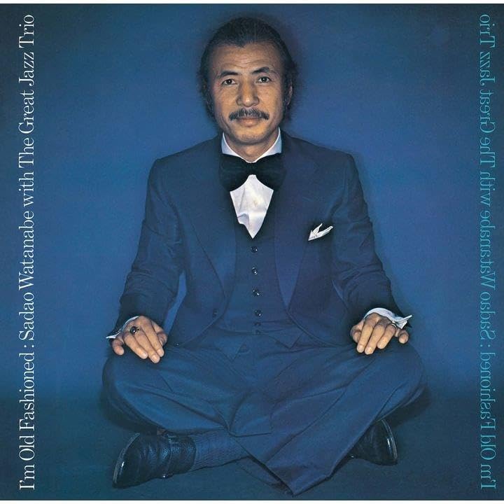 Sadao Watanabe portrait on CD cover, wearing a suit and seated.