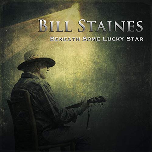 Bill Staines in a hat plays guitar under a spotlight on this album cover.