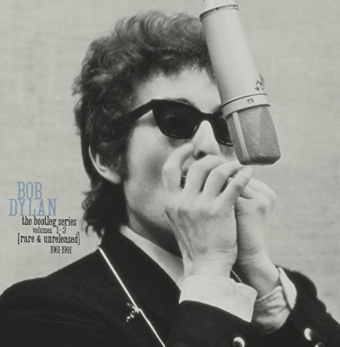 Bob Dylan in sunglasses speaking into a vintage microphone, album cover.