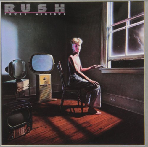 AlbumLanky shirtless man sitting in a room with vintage televisions near a window.