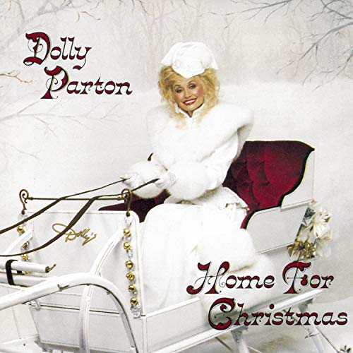 Dolly Parton in a white coat and hat, seated in a sleigh.