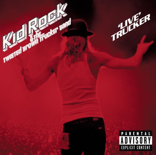 Kid Rock performing on stage in front of a crowd, bathed in red light.