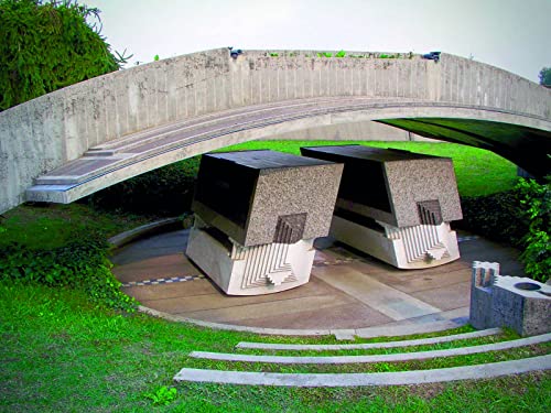 Concrete structures under a curved bridge, surrounded by green grass.