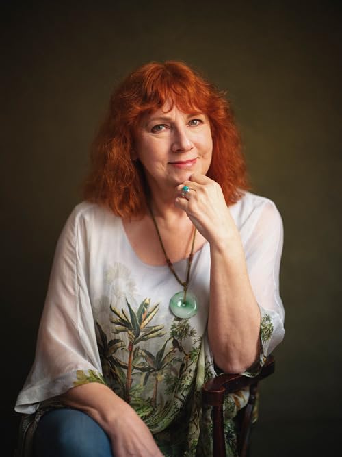 Portrait of author Kate Quinn with red hair and a thoughtful expression.