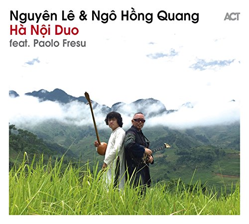 CD cover with musicians in a grassy field before misty mountains.