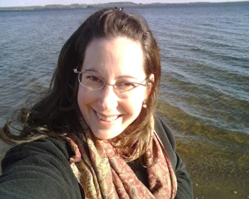 Woman with glasses smiling, standing outdoors near water.