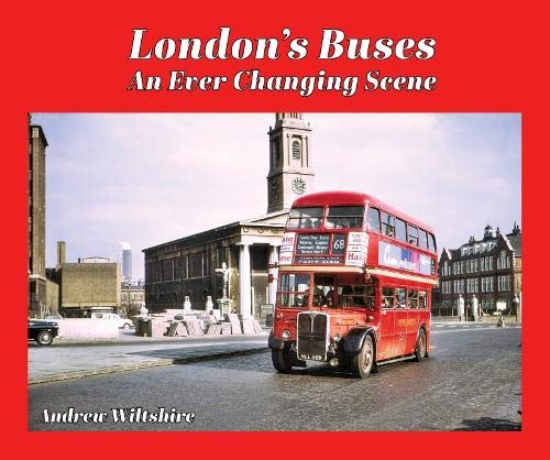 Red London double-decker bus travels past buildings and a clock tower.