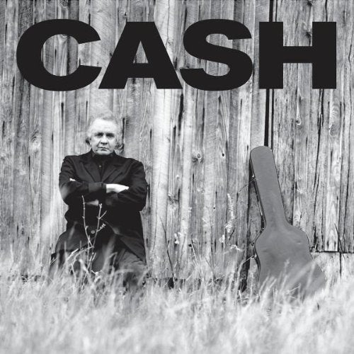 Black and white portrait of Johnny Cash with a guitar case.