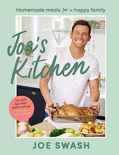 Joe Swash smiling in a kitchen holding a roasting pan with a cooked chicken.