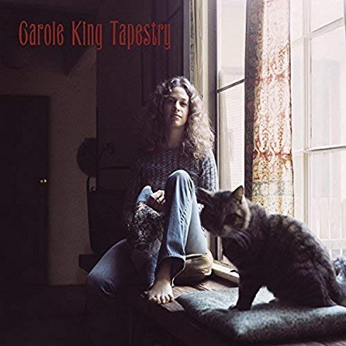 Carole King sits barefoot by a window with a cat on the album cover.