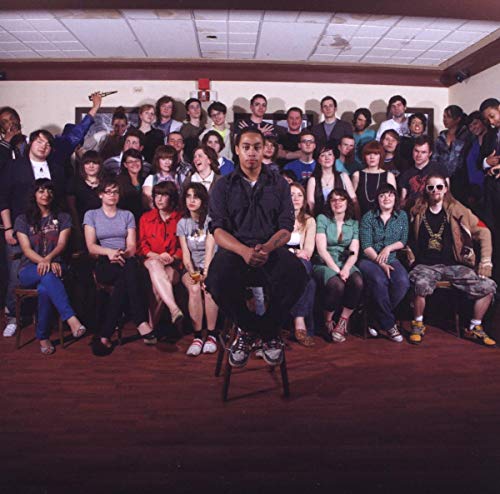 Group portrait of people seated and standing in a room, with a central figure.
