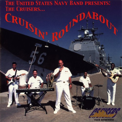 Five US Navy Band members in white uniforms performing in front of a warship.