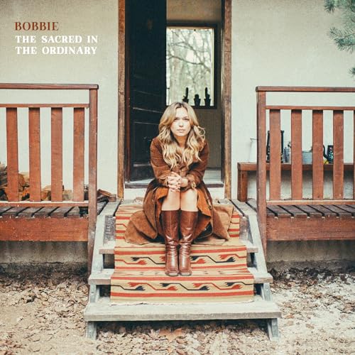 Woman with long hair sits on porch steps, album cover.