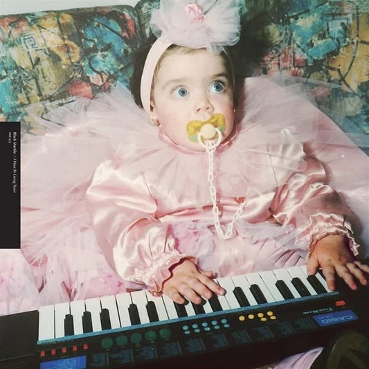 Baby with pacifier wearing pink, posed with a keyboard.