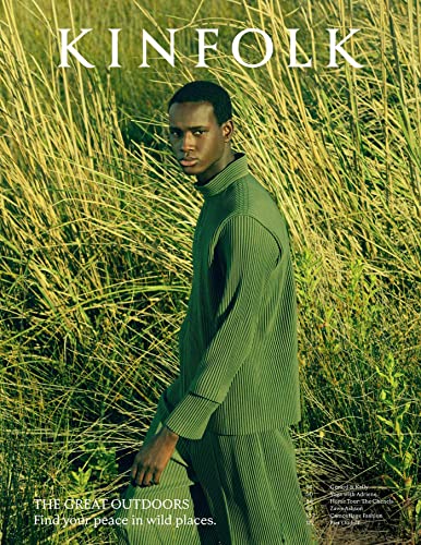 A man in a green pleated outfit standing in tall grass on a magazine cover.