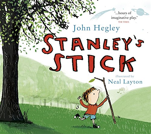 A boy holding a stick runs through a field near a large tree.