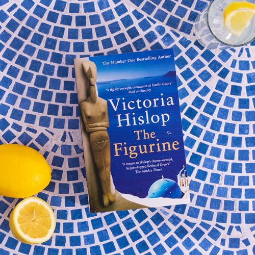 The Figurine book cover on a blue mosaic table with lemons and a drink.