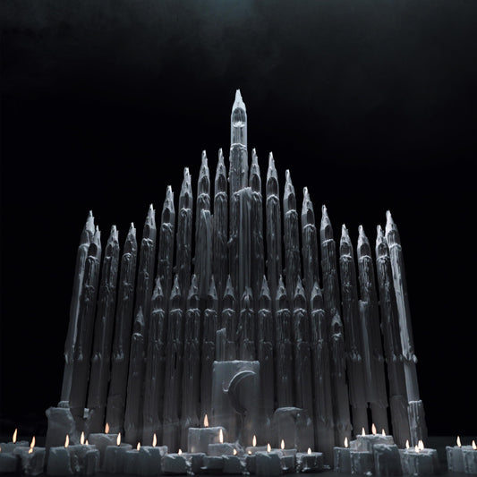 Tall, melting candles arranged like a gothic cathedral in darkness.