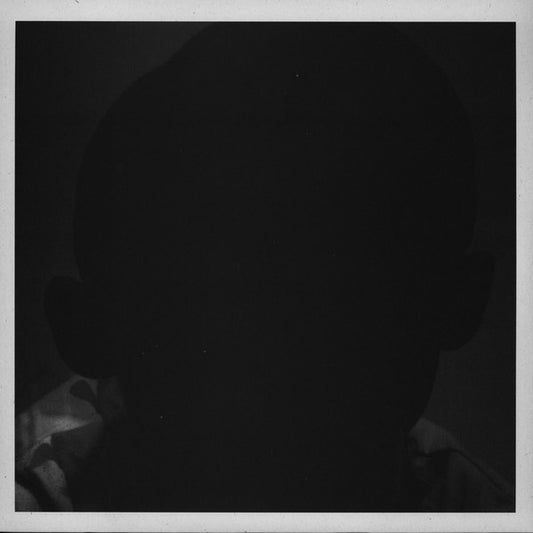 Black and white portrait of a person in shadow, facing away.