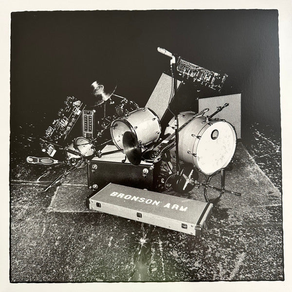 Black and white vinyl record cover featuring a band playing drums and equipment.