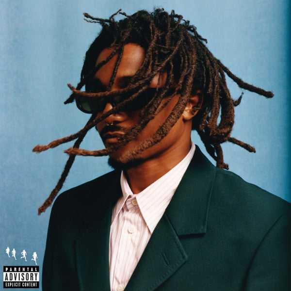 Portrait of a man with long dreadlocks and sunglasses, wearing a suit.