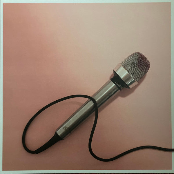 A silver microphone with a black cable against a soft pink gradient background.